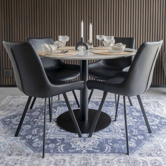 Moderne eetkamer met zwarte stoelen, luxe kaarsen en zwarte stoelen.