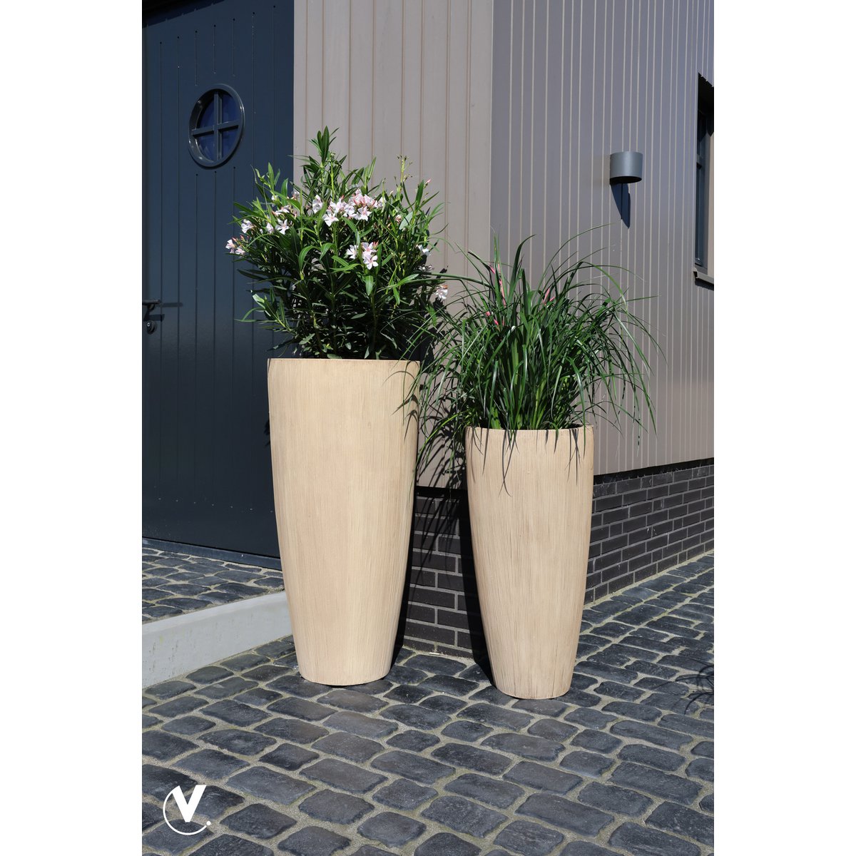Twee beige fiberstone plantenbakken Java in een grijze moderne tuin met verschillende planten