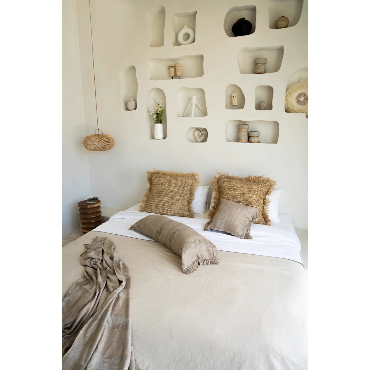 Beige raffia kussenhoes 60 X 60cm gestyled op een bed met allerlei dekentjes en beeldjes