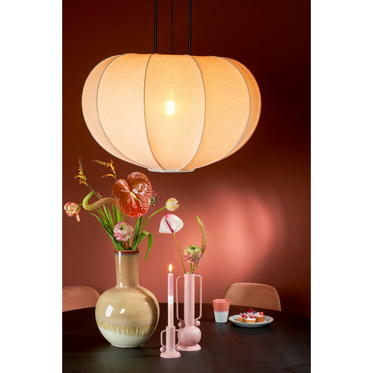 Beige keramieken vaas met een warme, natuurlijke uitstraling, in een warme rode moderne omgeving. Perfect om gedroogde bloemen of takken in te plaatsen, maar ook prachtig als los decoratief object. De aardse tinten en matte afwerking brengen een rustieke en mediterrane sfeer in elk interieur.