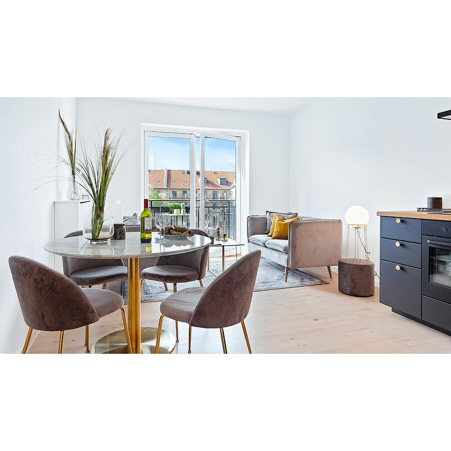 Grijze fluwelen eetkamerstoelen met goudkleurige poten rond een marmeren eettafel in een moderne woonkamer met veel licht. Een elegante en luxe combinatie die warmte en verfijning toevoegt aan het interieur.