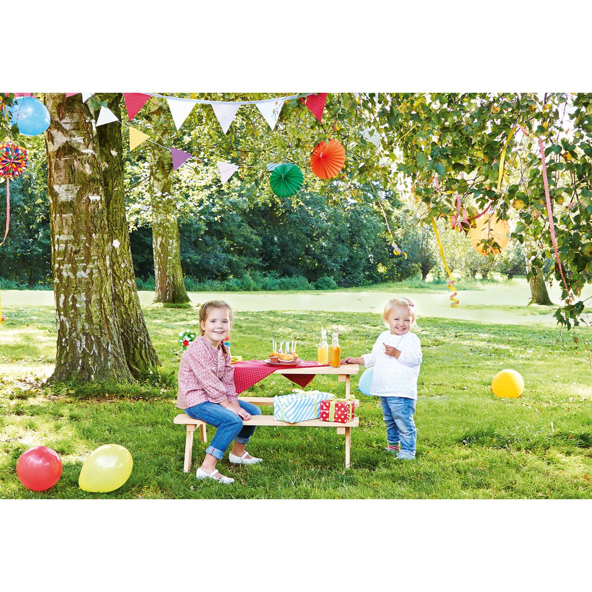 Picknickbank Nicki For 4 in een feestsetting met ballonnen en slingers. 2 Kinderen hebben plezier.
