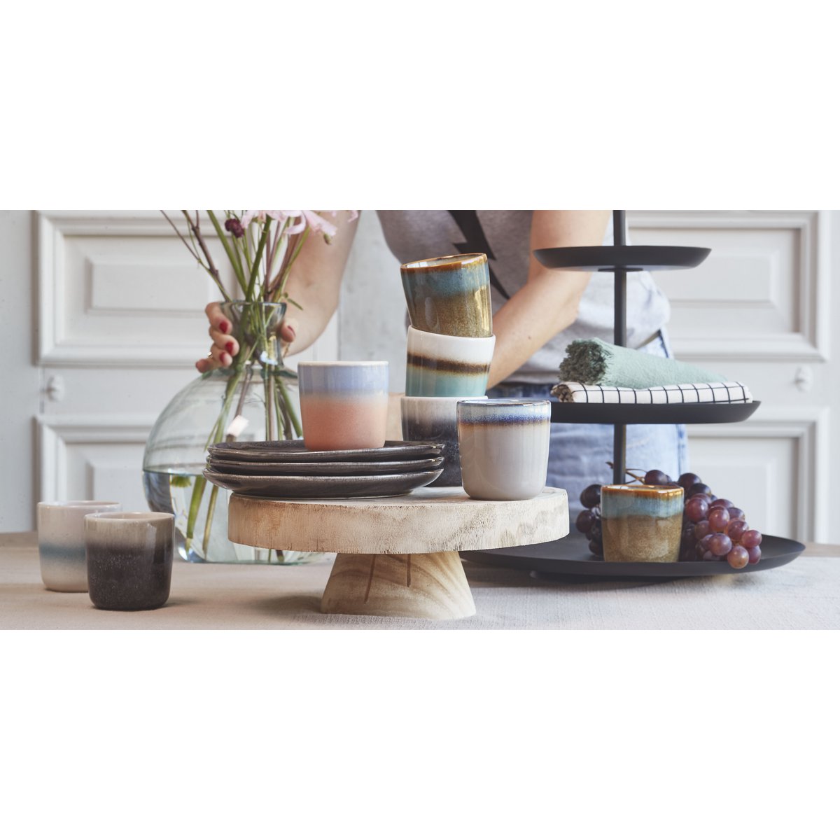 Ronde zwarte metalen 3-laagse etagere in sfeersetting, aangekleed op tafel met druiven, koekjes, chocola en nog veel meer.