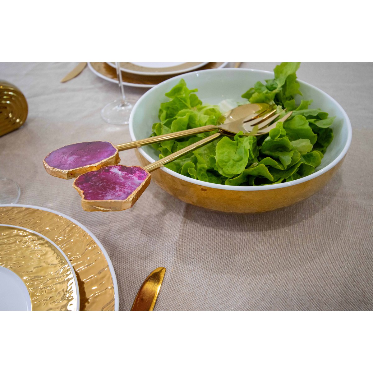 Saladebestek goud met roze agaat in een gouden saladebak met sla erin bij ander gouden servies