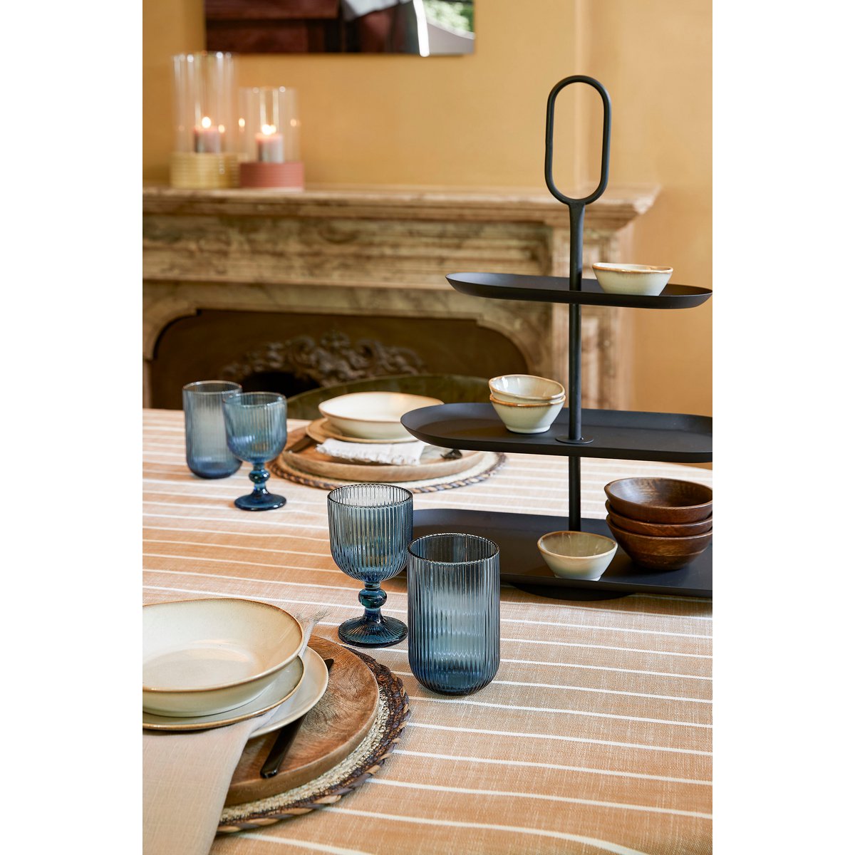 Zwarte metalen 3-laagse etagère Rama in een sfeervolle setting op tafel, perfect voor hapjes, koekjes, cake en andere lekkernijen en snacks.