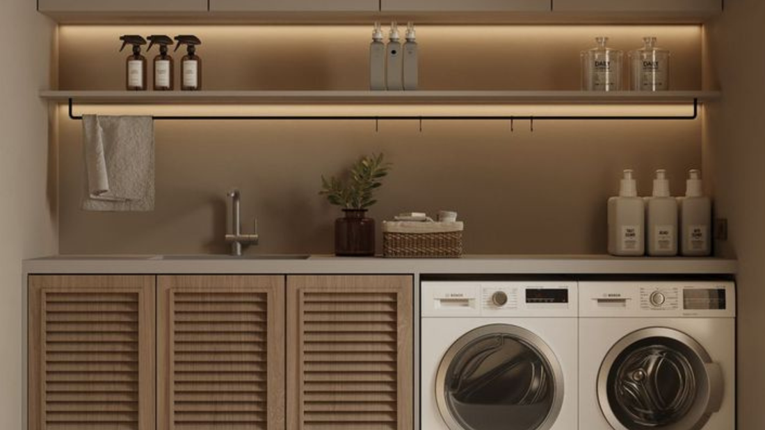 Warme bijkeuken met houten kastdeuren, wasmachine en droger onder werkblad, open plank met flessen en zachte verlichting, inspiratie voor wonen en interieur styling met natuurlijke materialen van Luben.