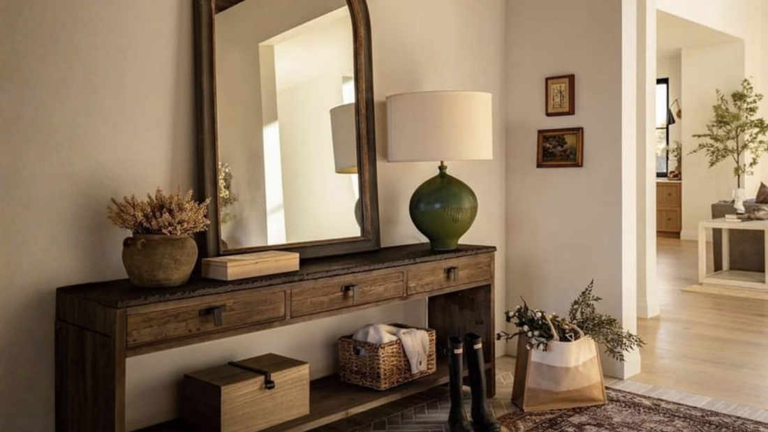 Hal met houten sidetable, grote spiegel, groene tafellamp en decoratieve manden, rustige wooninspiratie voor entree styling met meubels en woonaccessoires van Luben.