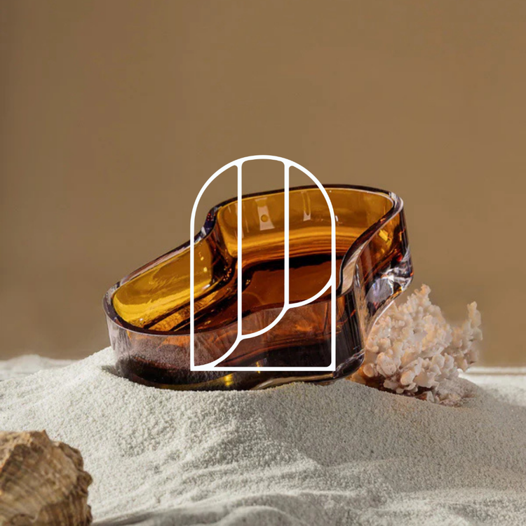 Afbeelding uit de collectie Decoratieve Schalen. Op de foto zie je een oranje schaal, sfeervol gestyled op wat zand met wat schelpen.