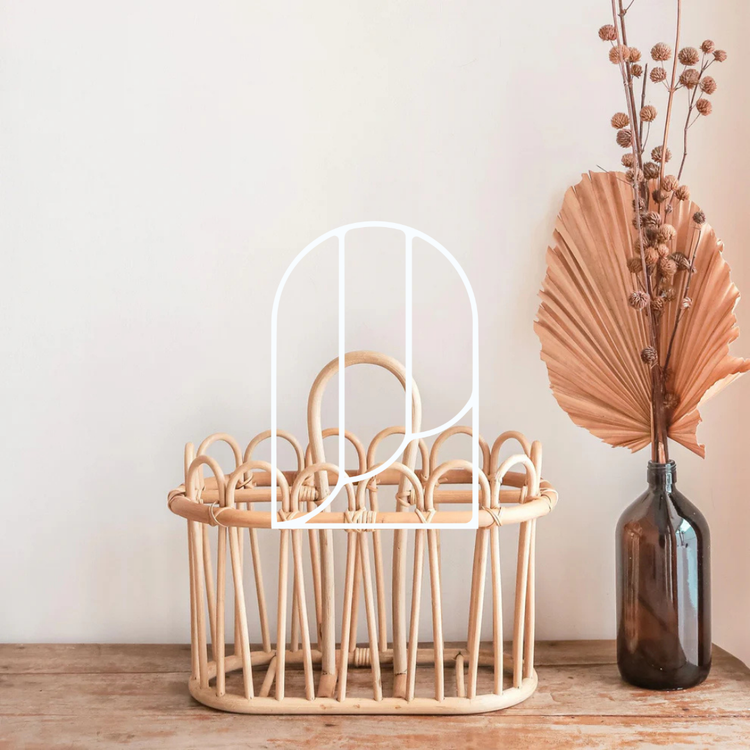 Afbeelding uit de collectie Tijdschriftenhouders. Op de foto zie je een rotan tijdschriftenhouder, met daarnaast een sfeervolle bruine vaas met planten en bloemen erin.