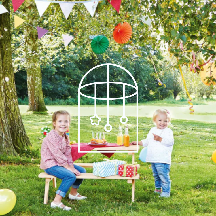 Afbeelding uit de collectie Tuin & Buitenspelen. Op de foto zie je twee kinderen bij een picknickbankje buiten op een groot groen veld. De tafel is leuk gedecoreerd met vrolijke spulletjes.