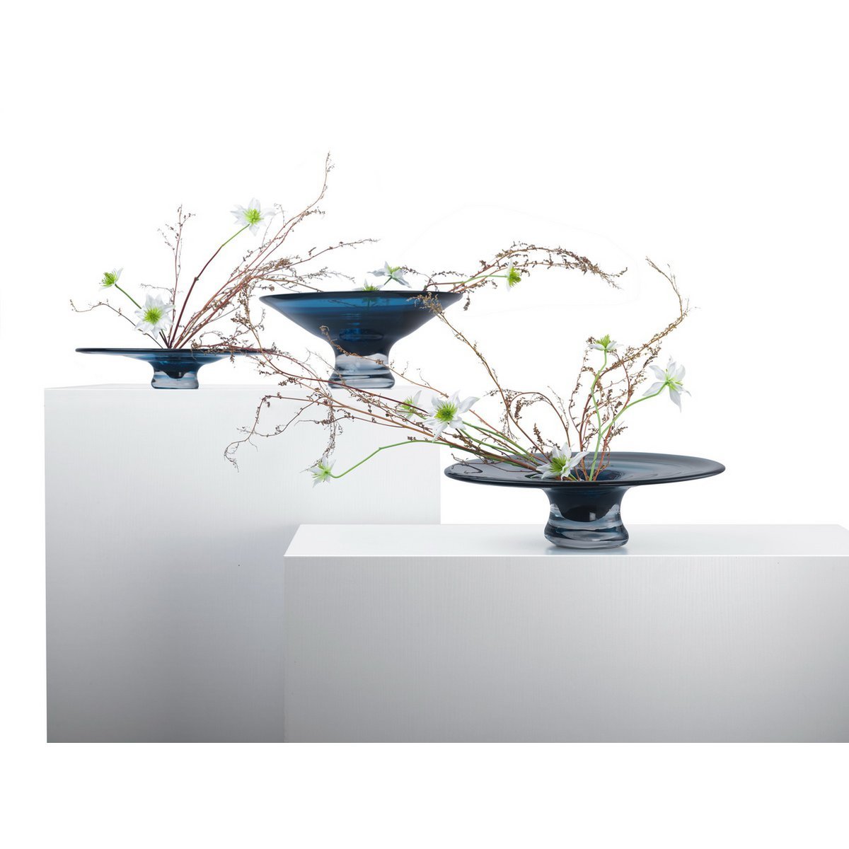 3 glazen taartplateau inktblauw rond 32 cm Alain op witte kastjes, verbonden met stengels van bloemen vanaf de zijkant
