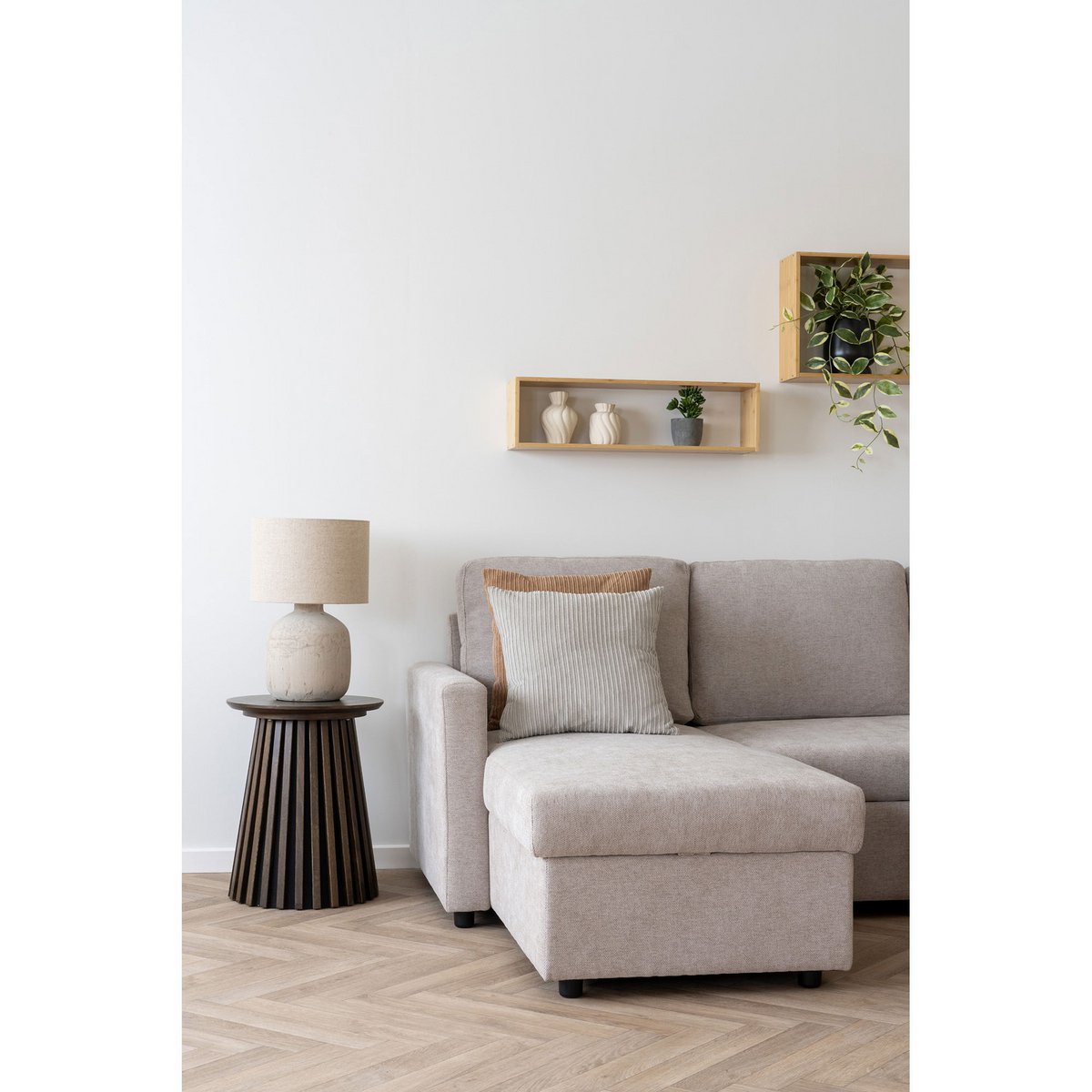 Bamboe wandplank naturel Ember, samen met een andere wandplank, gestyled met vaasjes en plantjes boven grijze bank en donker nachkastje.