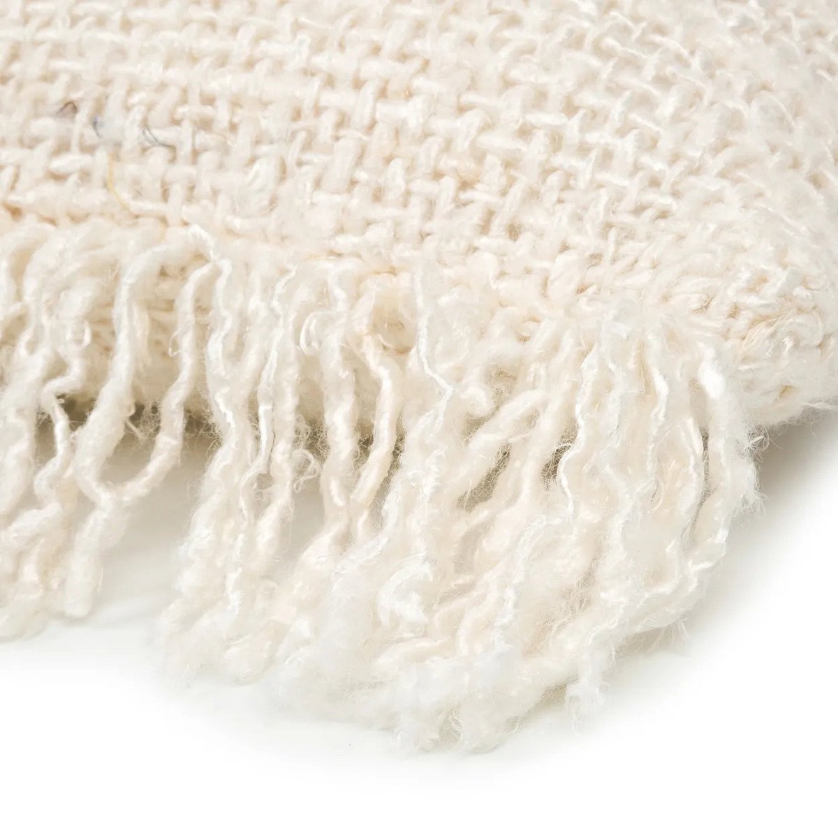 Detailfoto van de geweven textuur en franjes van de naturel kussenhoes