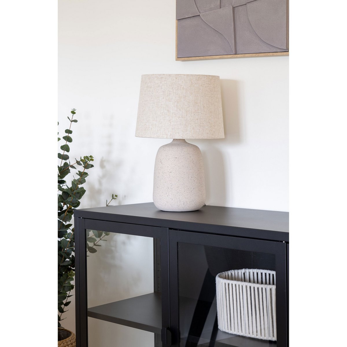 Steenbeige tafellamp gestyled op een zwarte sidetable in modern interieur