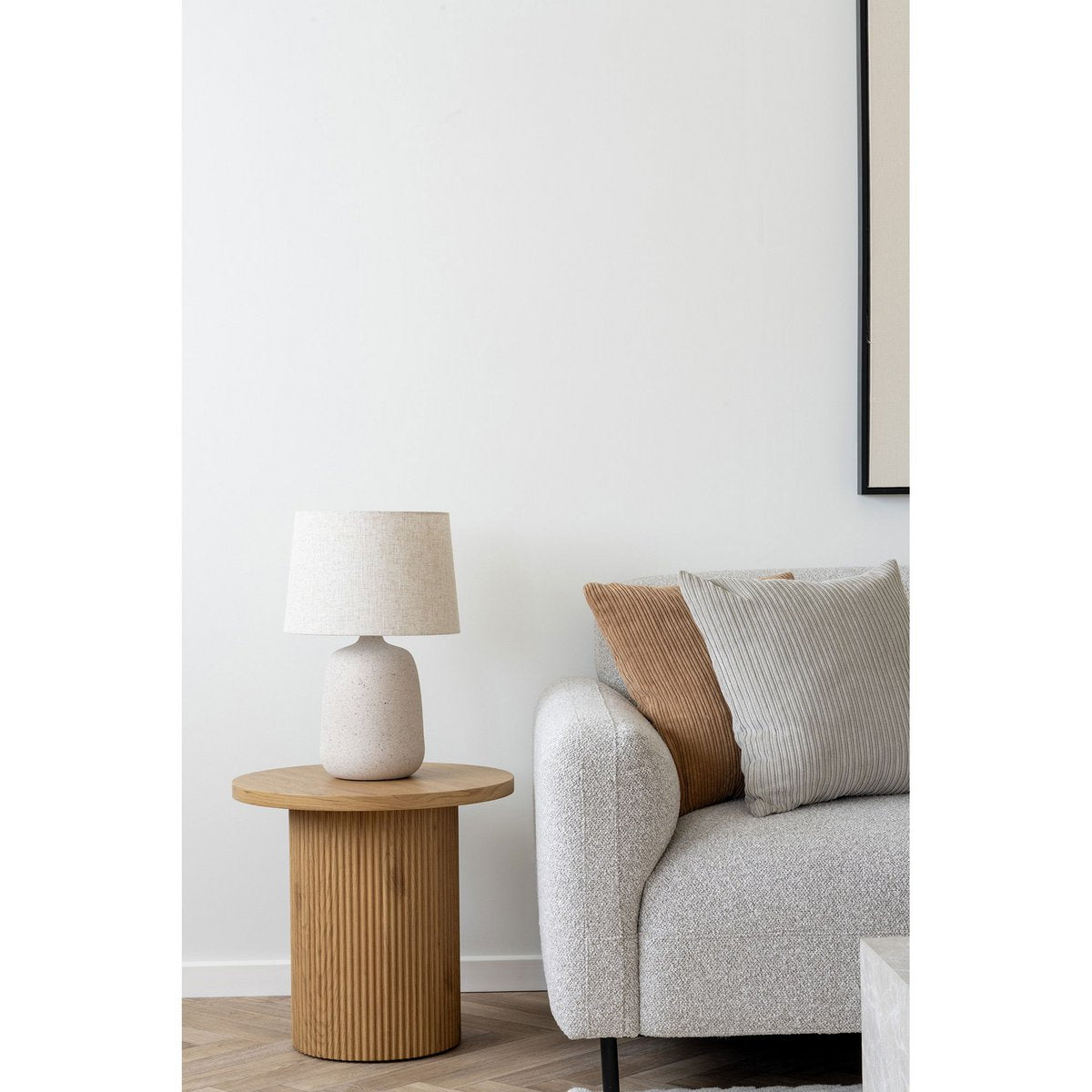 Tafellamp keramiek beige naast bank in warm minimalistisch interieur
