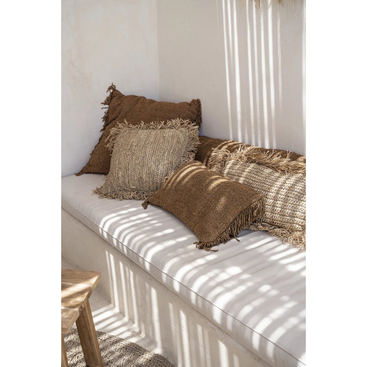 Close-up van de kussenhoes op een bedbank met andere naturel kussens.