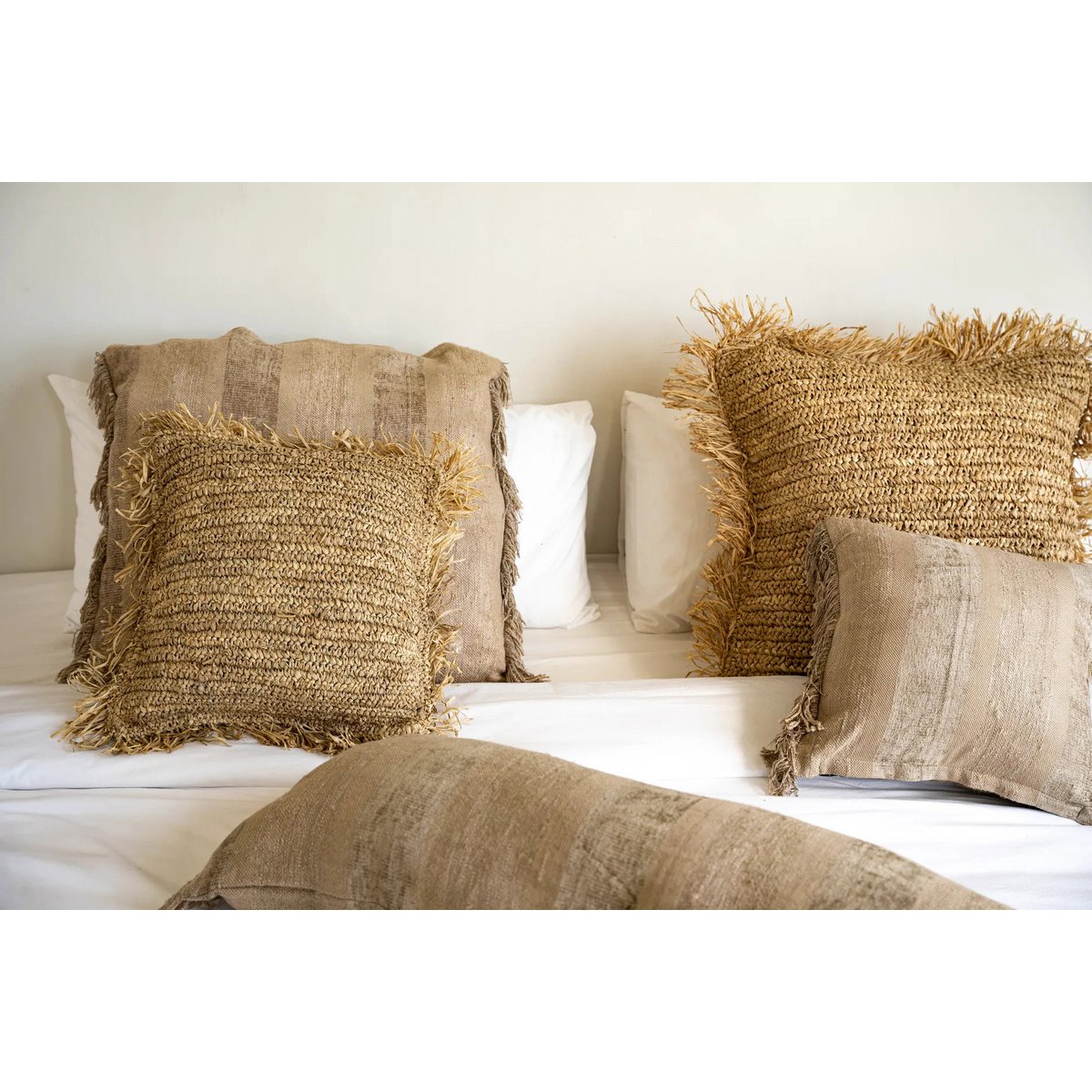 De raffia kussenhoes gestyled op een bank met natuurlijke tinten.