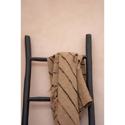 Handgeweven plaid over zwarte ladder – natuurlijke deken met rustieke uitstraling.

