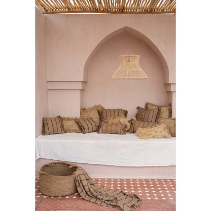 Beige-zwart gestreepte plaid in mediterrane setting – warme woondeken van natuurlijke materialen.
