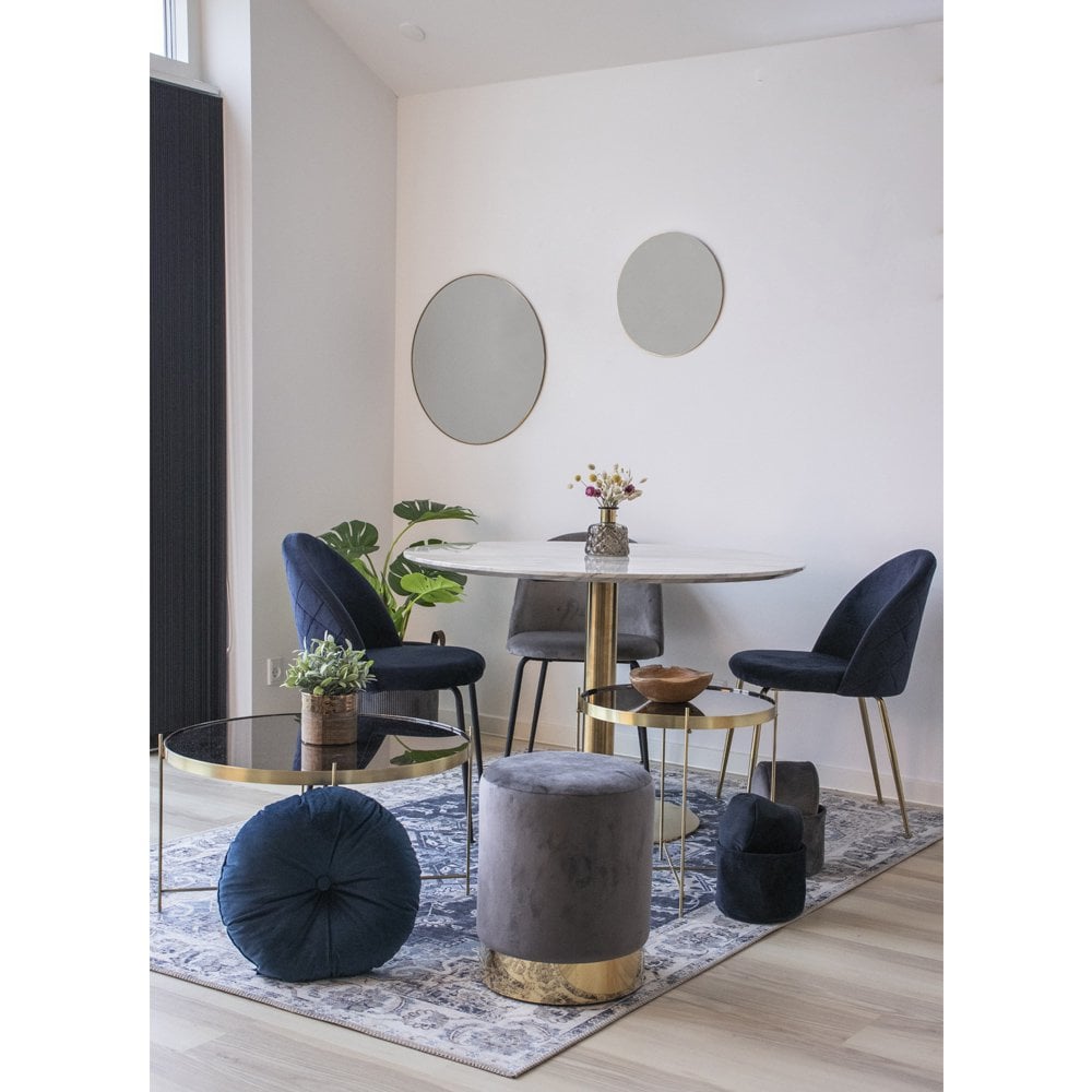 Blauwe fluwelen eetkamerstoelen met goudkleurige poten rond een marmeren eettafel in een moderne eetkamer met stijlvolle accenten. Een luxe en elegante combinatie die warmte en klasse toevoegt aan het interieur.