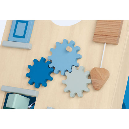 Close-up van houten activiteitenbord met tandwielen, kralen en spiegel in blauwe en grijze tinten.