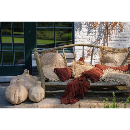 Bordeaux fluwelen kussen gestyled op een tuinbank met aardetinten in het interieur