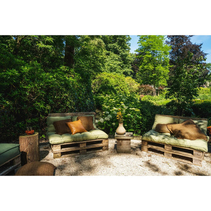 Bruine Oh My Gee kussenhoes buiten gestyled tussen houten decoratie en groen landschap