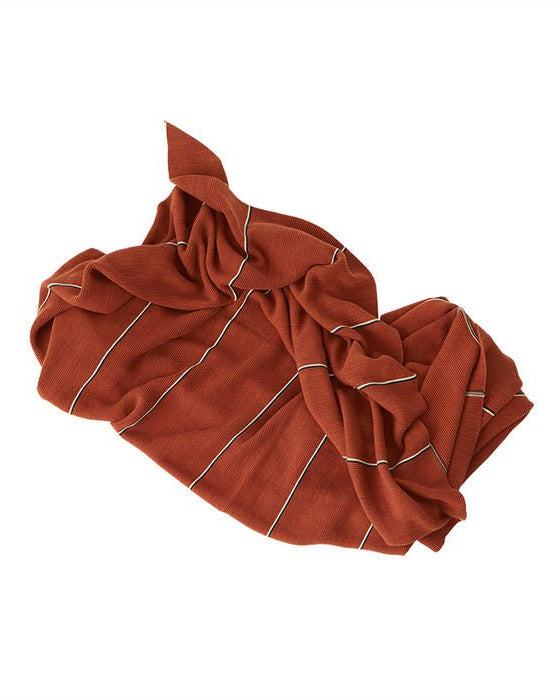 Warmte in zijn mooiste vorm. Dit gebreide plaid in roestbruine tint met subtiele streepjes is perfect voor koude dagen en knusse avonden.
