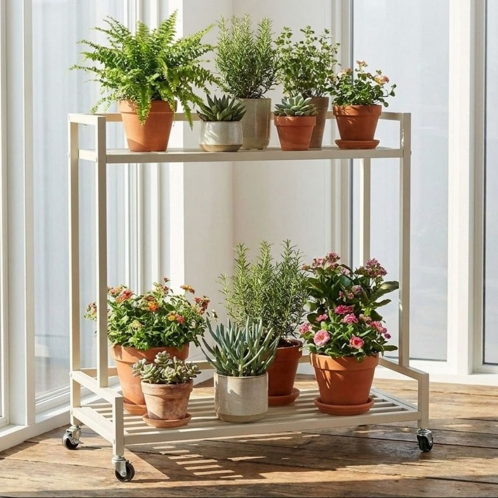 De metalen plantenstandaard op wielen gebroken wit 81 cm binnen in een witte kamer met verschillende potten en planten erop