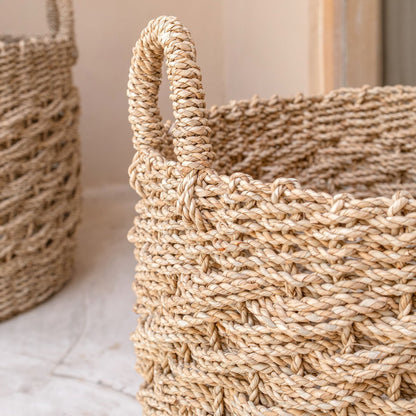 Detail van de twee zeegras manden rond naturel met handvatten Masila naast elkaar in een hoek van de badkamer