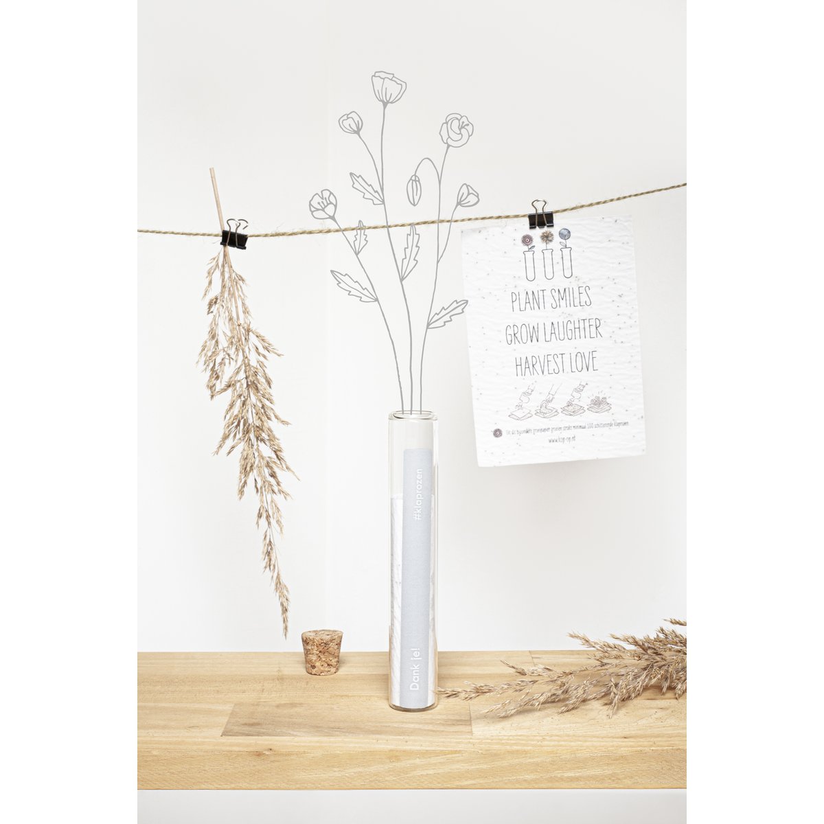 Glazen buisje met groeipapier op houten tafel met droogbloemen en plantkaart aan touw