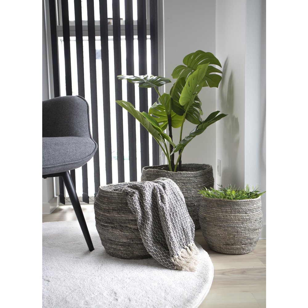 Grijze manden van maïsblad gestyled in woonkamer met plant en plaid