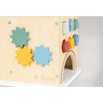 Close-up van houten speelkubus met vrolijke vormen, tandwielen en regenboogboog.