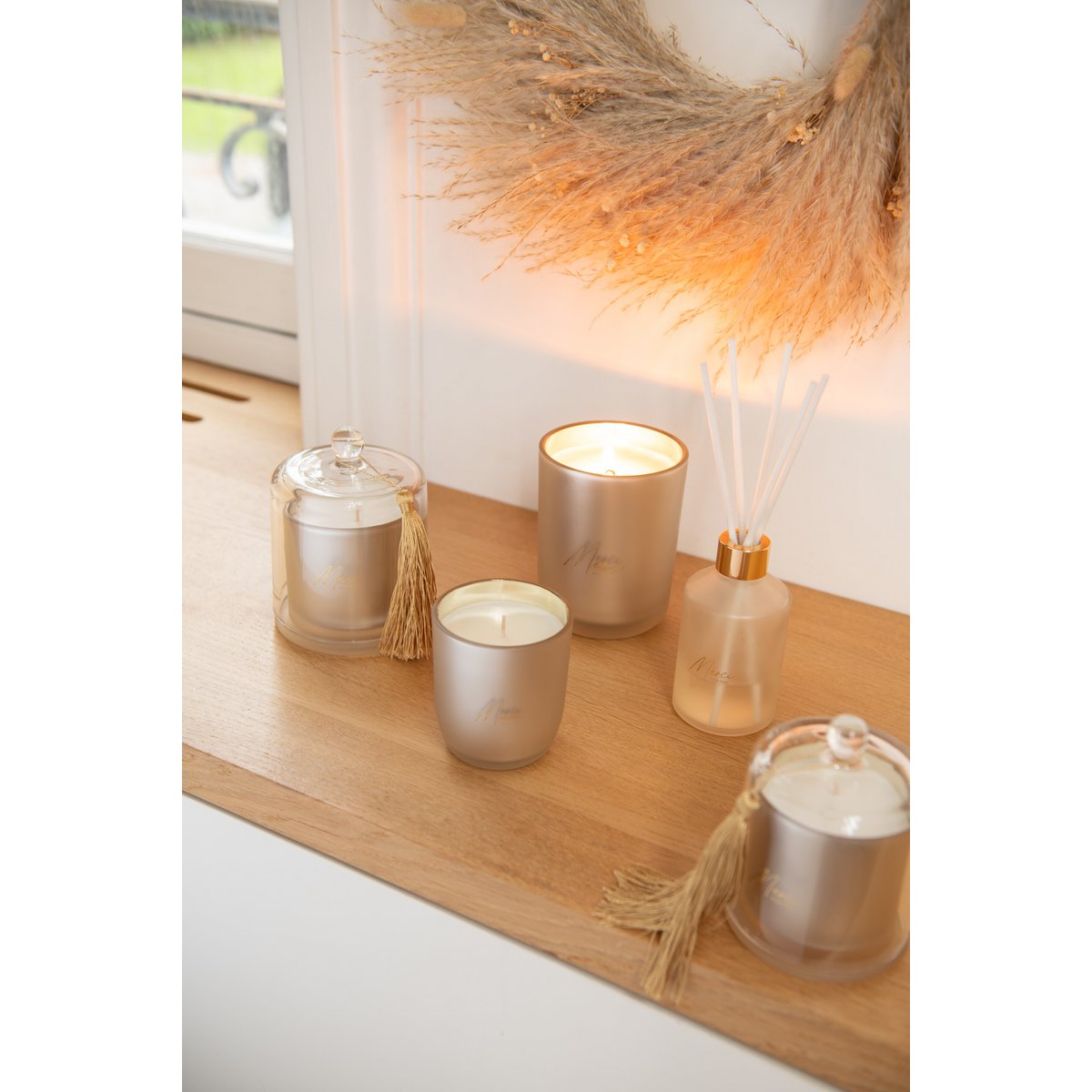 J-Line geurkaars beige glazen pot 10 cm Merci op een houten aanrecht met andere artikelen uit dezelfde lijn