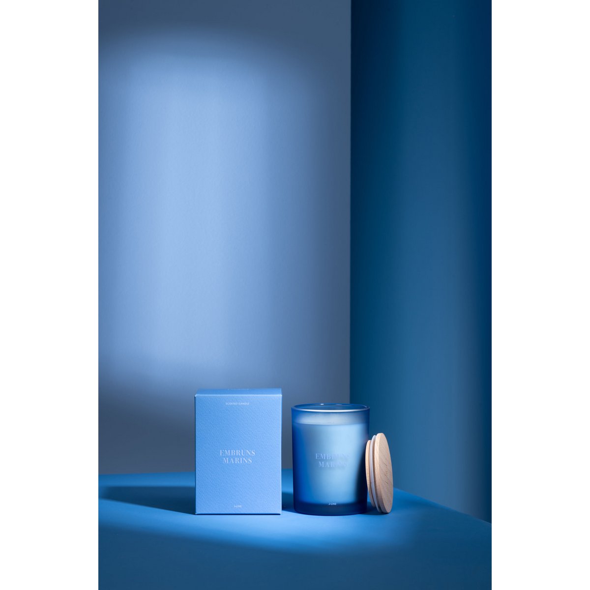 J-Line geurkaars blauw glazen pot zeebries 12,5 cm Accords Essentiels naast de verpakking in blauwe sfeervolle ruimte