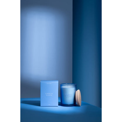 J-Line geurkaars blauw glazen pot zeebries 12,5 cm Accords Essentiels naast de verpakking in blauwe sfeervolle ruimte