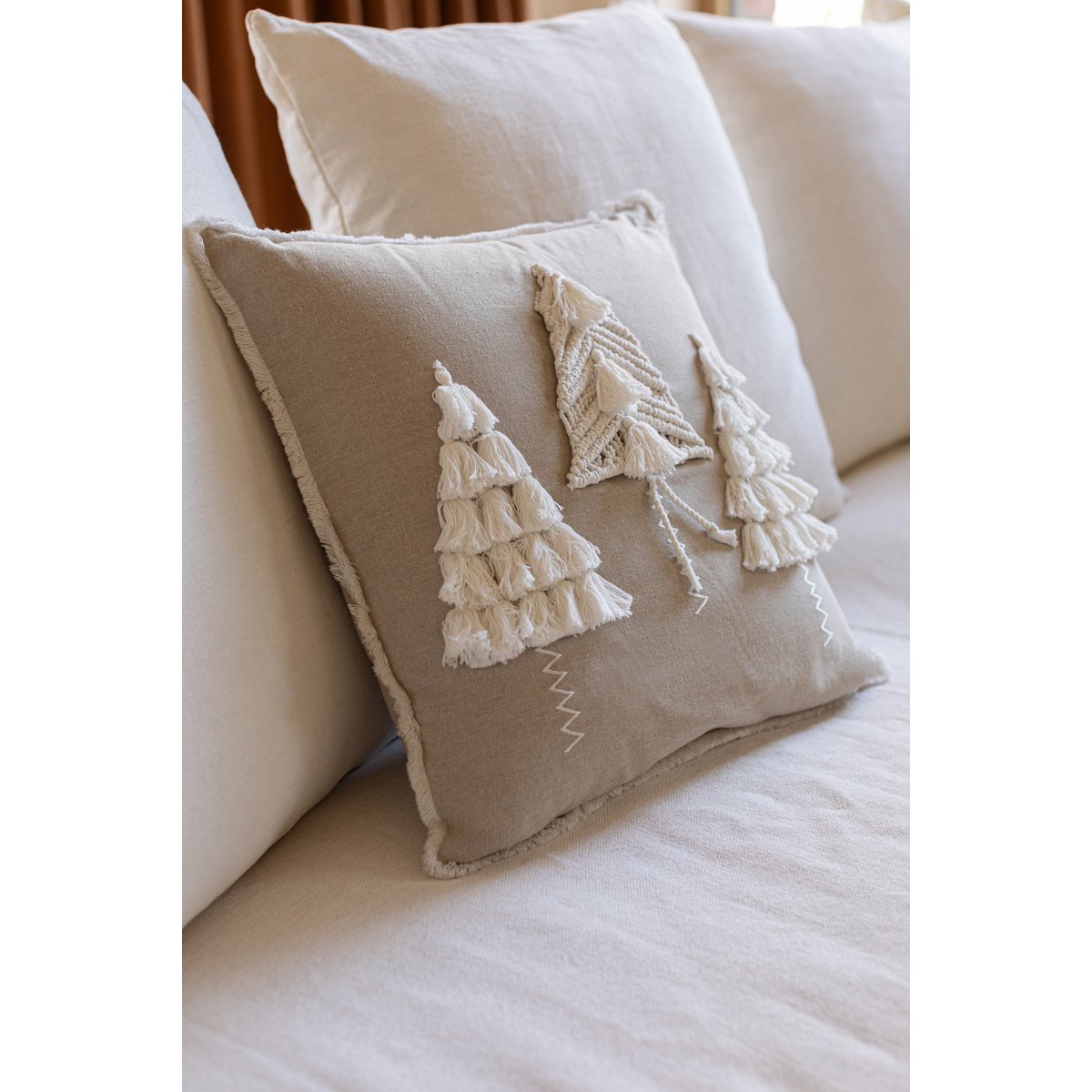 J-Line kerstkussen beige en wit met kwasten, op een witte bank
