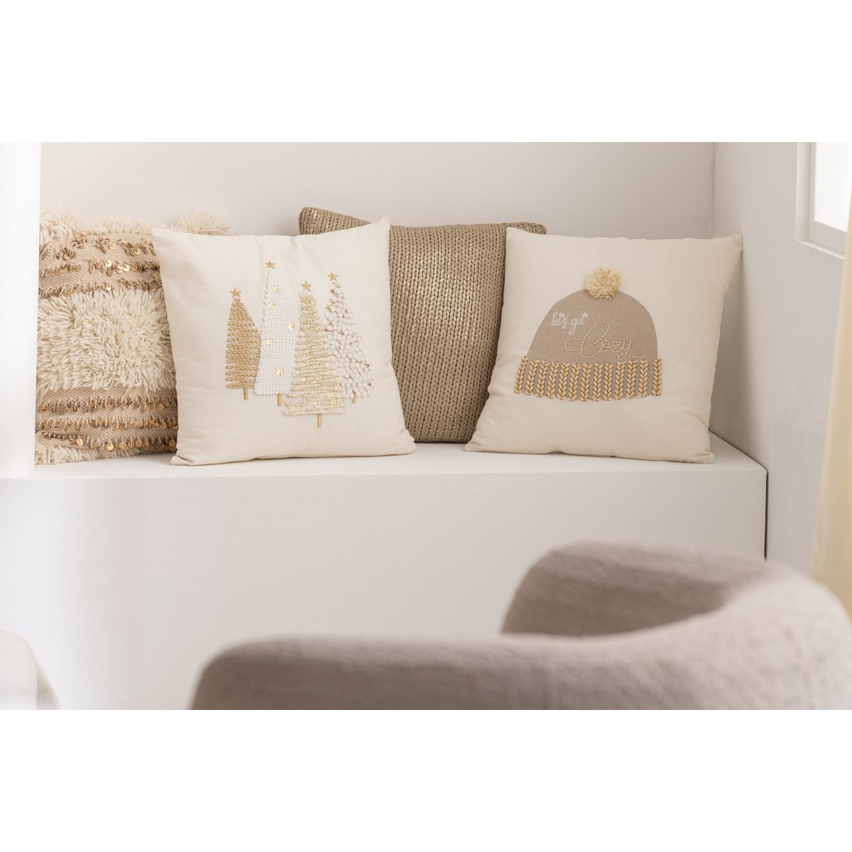 J-Line kerstkussen wit met gouden kerstbomen, op witte kastjes als decoratie samen met andere wit met gouden kussens