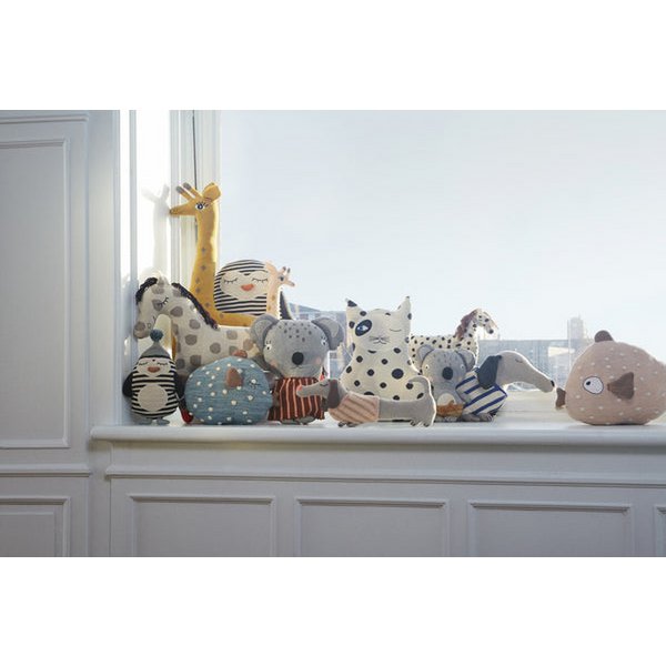 Gebreide knuffels in verschillende dierenvormen op een vensterbank, waaronder een giraffe, kat, koala en teckel – stijlvolle kinderkamerdecoratie in zachte kleuren.