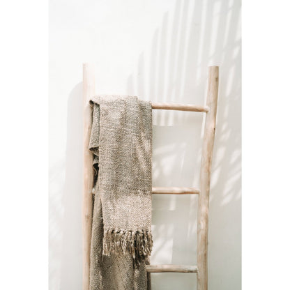 Beige plaid hangend over houten ladder – stijlvolle woondecoratie met rustieke uitstraling.