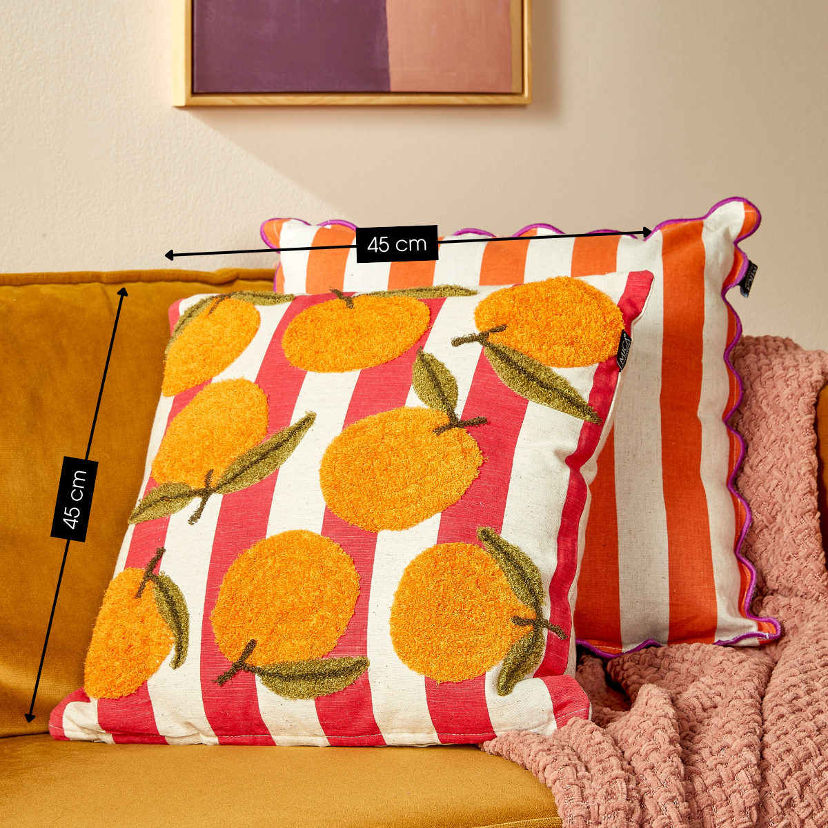Katoenen sierkussen rood met sinaasappelprint 45x45 cm op een oranje bank met kleurrijke kussens en plaids