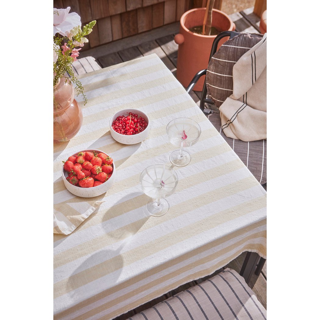 Katoenen tafelkleed vanille gestreept 200x140 cm op een tafel met glazen drinken en schalen met fruit