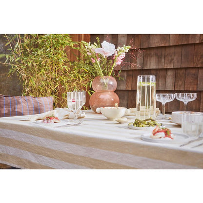 Katoenen tafelkleed vanille gestreept 200x140 cm op een tafel met glazen drinken, schalen met fruit en vazen met bloemen