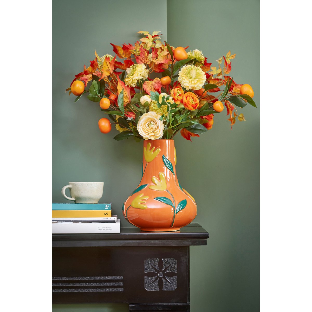 Keramieken vaas oranje met bloemmotief 30 cm Ava op een houten tafel tegen groene achtergrond, met grote oranje en gele bloemen