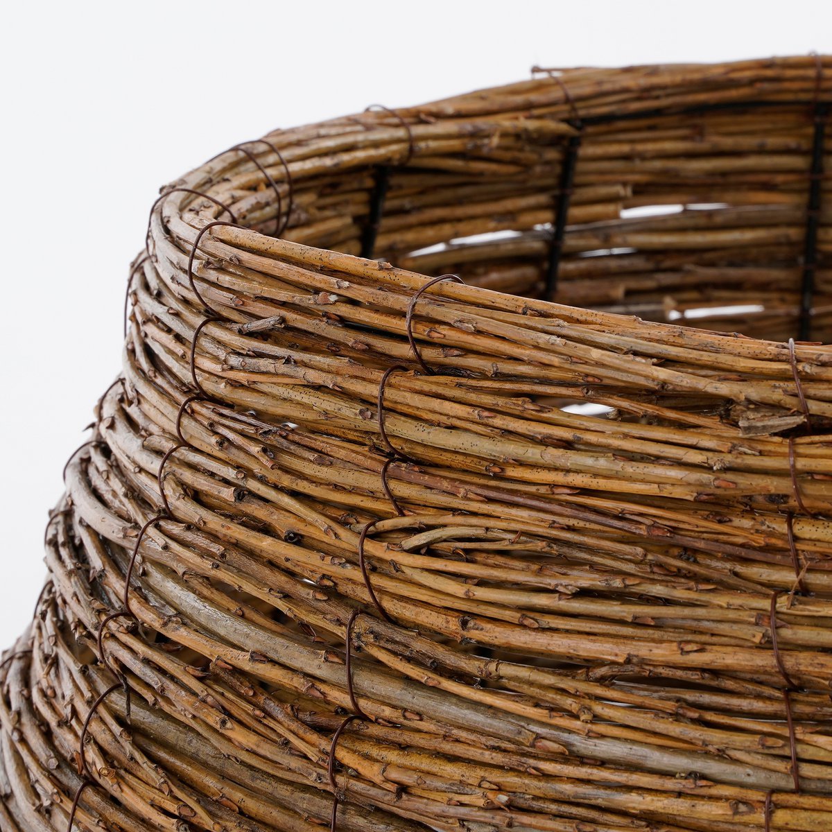 Detail van handgevlochten wilgentakken – ambachtelijk geweven kerstboommand met warme bruine tint.
