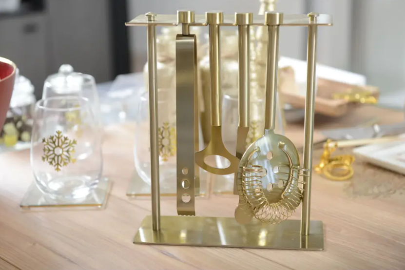 Keukengerei houder goud met keukengerei set 5-delig op een tafel met witte en gouden glazen en decoratie