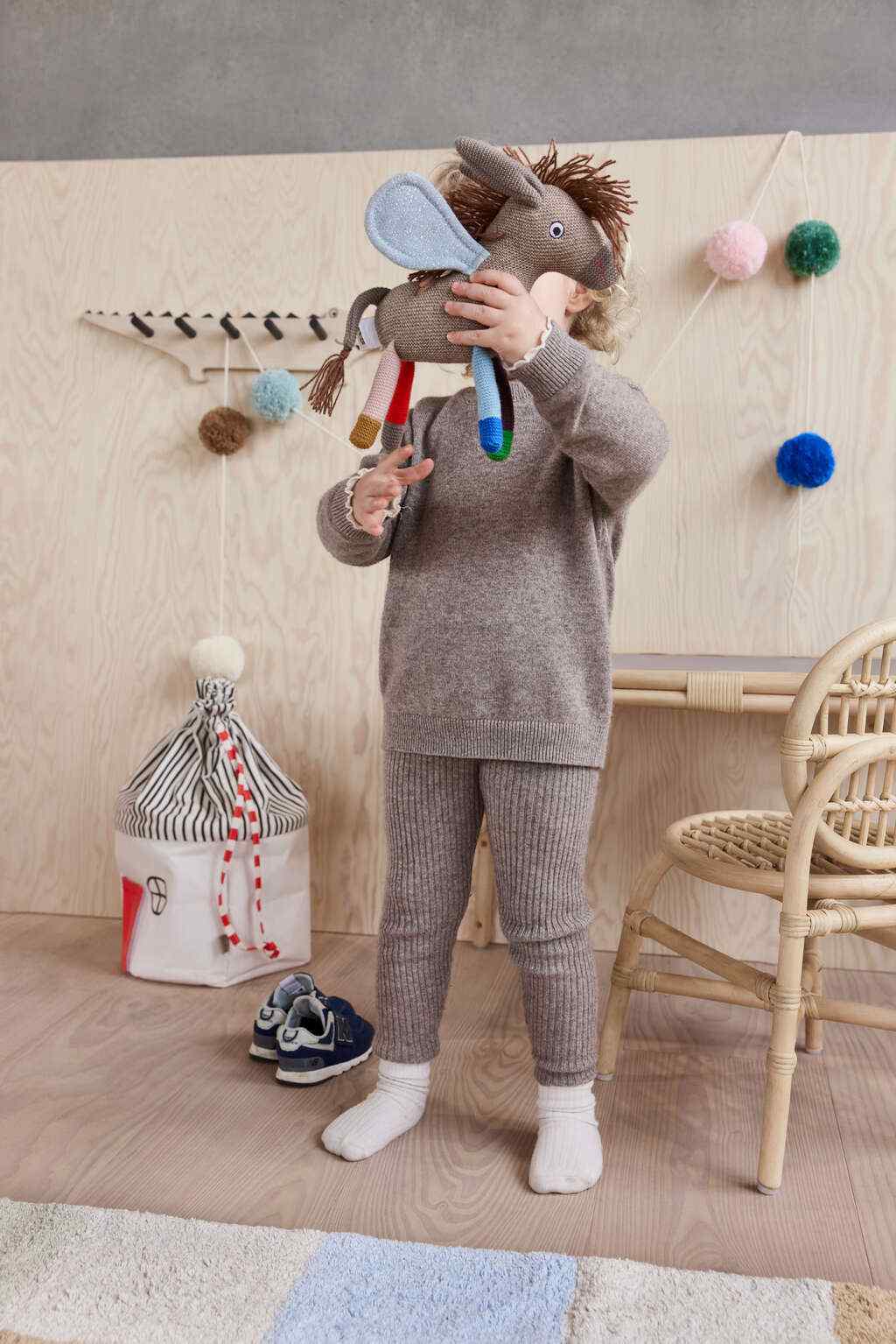 Knuffel ezel Donny Sky met vleugels in de handen van een kindje, in een houten speelkamer