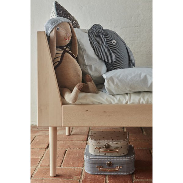 Knuffel olifant Erik blauw gestreept op een bed met witte kussens naast een konijnenknuffel