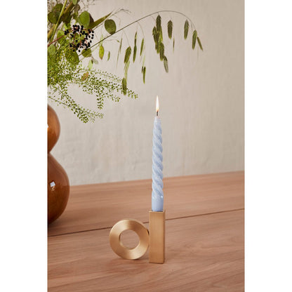 Matgouden kandelaar met blauwe en witte kaars – stijlvolle tafeldecoratie in modern interieur.
