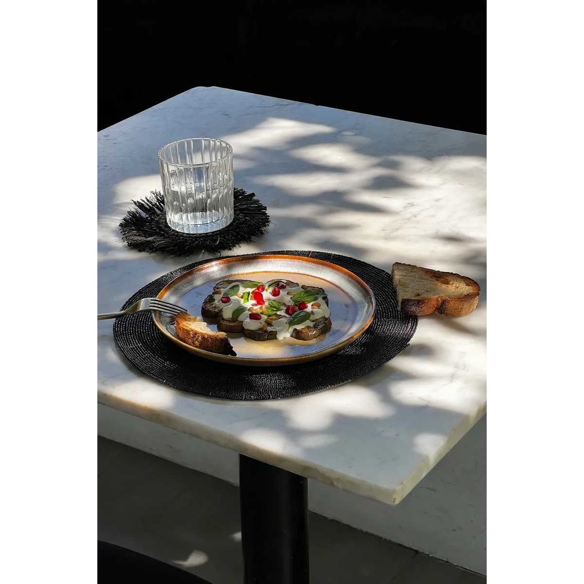 Kralen placemat zwart 30 cm met daarop een bord met lekker eten